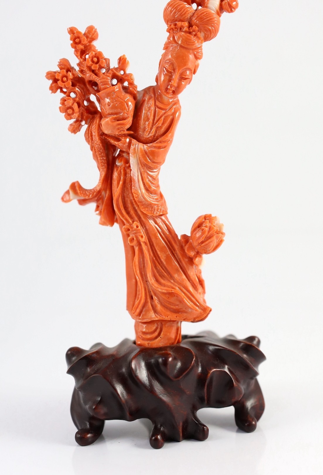 A Chinese carved coral figure of a flower fairy, 20th century, the carving 19cm high and 119g, wood stand